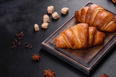 Delicious fresh crispy croissants on a dark concrete background. Tasty breakfast