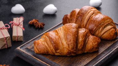 Delicious fresh crispy croissants on a dark concrete background. Tasty breakfast