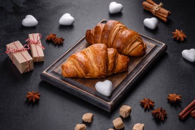 Delicious fresh crispy croissants on a dark concrete background. Tasty breakfast