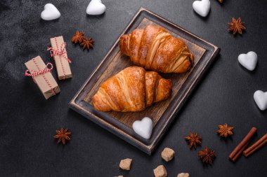 Delicious fresh crispy croissants on a dark concrete background. Tasty breakfast
