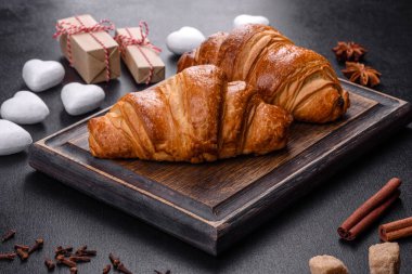 Delicious fresh crispy croissants on a dark concrete background. Tasty breakfast
