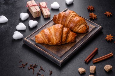 Delicious fresh crispy croissants on a dark concrete background. Tasty breakfast