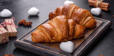 Delicious fresh crispy croissants on a dark concrete background. Tasty breakfast
