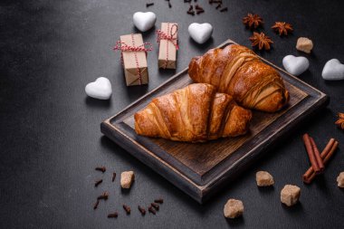 Delicious fresh crispy croissants on a dark concrete background. Tasty breakfast