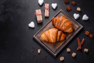 Delicious fresh crispy croissants on a dark concrete background. Tasty breakfast