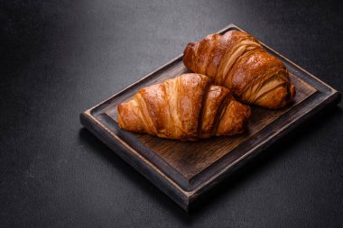 Delicious fresh crispy croissants on a dark concrete background. Tasty breakfast