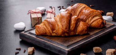 Delicious fresh crispy croissants on a dark concrete background. Tasty breakfast
