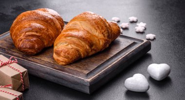 Delicious fresh crispy croissants on a dark concrete background. Tasty breakfast