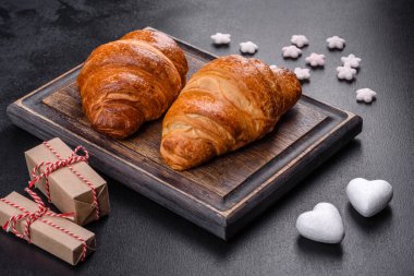 Delicious fresh crispy croissants on a dark concrete background. Tasty breakfast