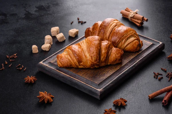 Delicious fresh crispy croissants on a dark concrete background. Tasty breakfast