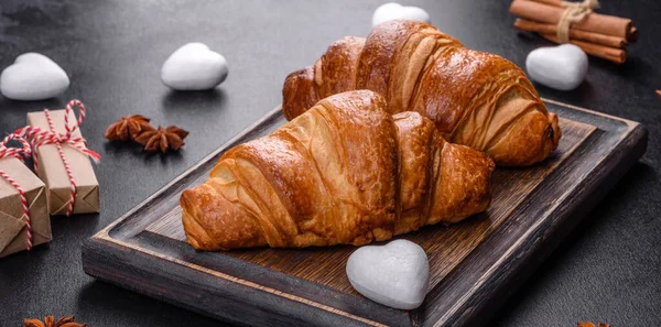 Delicious fresh crispy croissants on a dark concrete background. Tasty breakfast