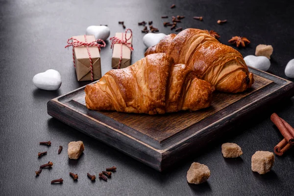 Delicious fresh crispy croissants on a dark concrete background. Tasty breakfast
