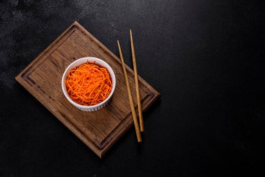 Vegetable appetizer Korean carrots with garlic and pepper and parsley in a bowl on a dark background