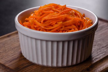 Vegetable appetizer Korean carrots with garlic and pepper and parsley in a bowl on a dark background