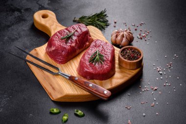 Kesme tahtasında çiğ biftek ve arka planda baharatlar.