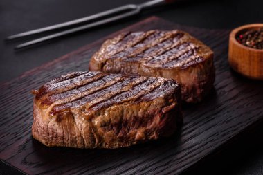 Karanlık bir arka planda taze sulu lezzetli biftek. Baharatlı ve otlu et yemeği.