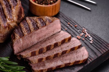 Karanlık bir arka planda taze sulu lezzetli biftek. Baharatlı ve otlu et yemeği.