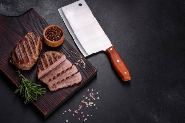 Karanlık bir arka planda taze sulu lezzetli biftek. Baharatlı ve otlu et yemeği.