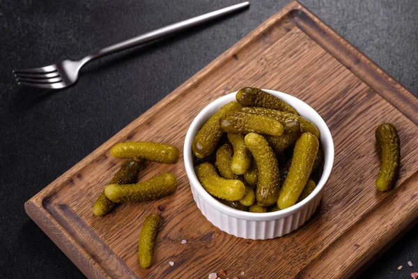 Beautiful pickled cucumbers of small size on a dark concrete background. Preparation of the festive table