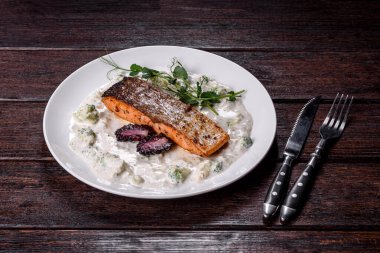 Brokoli, beyaz sos ve bezelye filizli beyaz bir tabakta lezzetli pişmiş somon balığı.