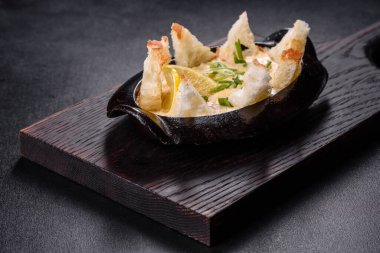 Peynir ve ekmek kırıntılarıyla pişirilmiş lezzetli bir deniz ürünleri tabağı. Baharat ve otlarla dolu dökme demir bir kasede.