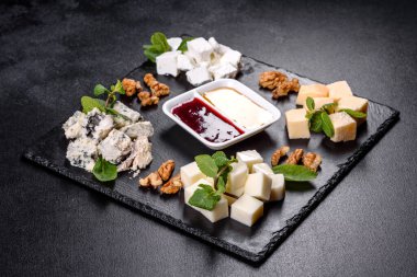 Naneli ve tatlı soslu şist tepsisinde çeşitli peynir çeşitleri. Şenlik masasına atıştırmalıklar