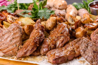 Ahşap tepside baharat ve otlarla pişirilmiş birkaç çeşit et. Büyük bir şirket için masa hazırlanıyor.