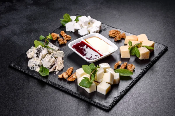 Naneli ve tatlı soslu şist tepsisinde çeşitli peynir çeşitleri. Şenlik masasına atıştırmalıklar