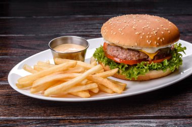 Karanlık bir masada sığır burger ve patates kızartması.