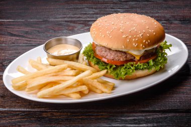 Karanlık bir masada sığır burger ve patates kızartması.