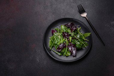 Kollu taze lezzetli salata, ıspanak ve siyah tabakta zeytinyağı ile pancar yaprakları. Lezzetli sağlıklı yemek.