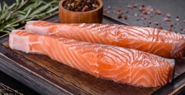 Somon balığı. Pişirme malzemeleri ve siyah arka planda bitkilerle taze çiğ somon balığı filetosu.