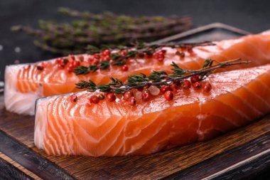 Somon balığı. Pişirme malzemeleri ve siyah arka planda bitkilerle taze çiğ somon balığı filetosu.