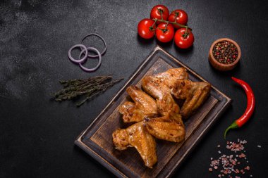 Siyah arka planda sebze ve baharatlı kızarmış tavuk kanadı.