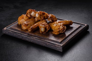 Siyah arka planda sebze ve baharatlı kızarmış tavuk kanadı.