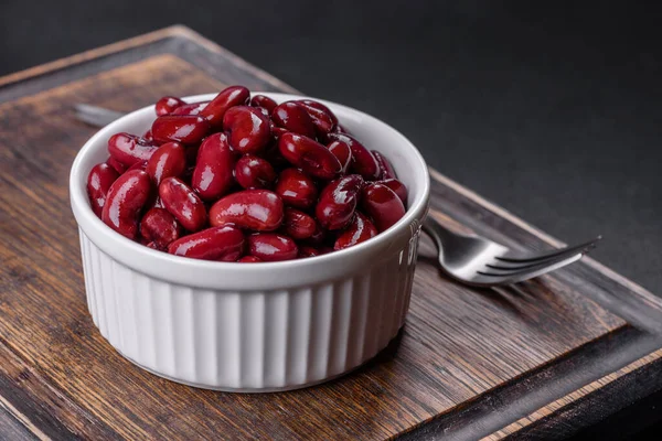 Tasty canned red beans in a beautiful white bowl on a wooden board