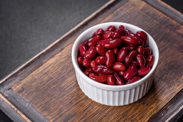 Tasty canned red beans in a beautiful white bowl on a wooden board