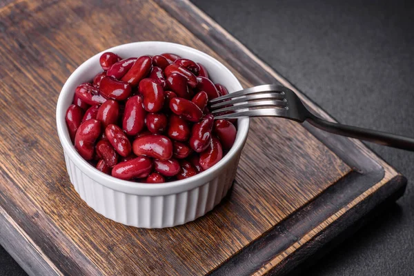 Tasty canned red beans in a beautiful white bowl on a wooden board