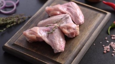 Tavuk kanatları, siyah arka planda, tahta bir tahtanın üzerinde yatar.