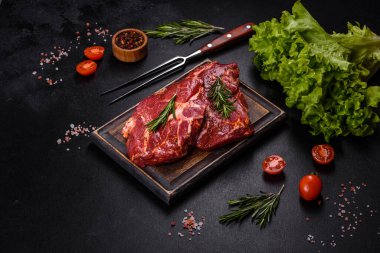 Çiğ biftek ve ahşap bir tahtada pişirmek için malzemeler.