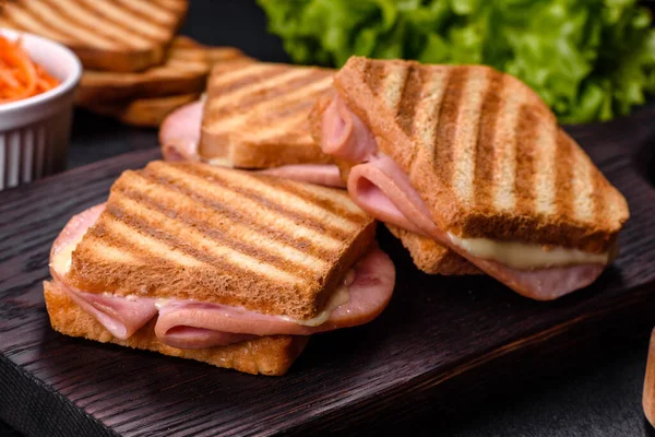 Toasted sandwiches with salami and melted cheese on black background