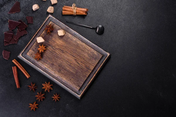 Şeker, tarçın ve diğer baharatlar koyu beton arka planda tahta kesme tahtasının üzerinde