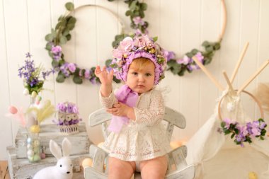 Renkli yumurtaları olan mutlu Paskalya tavşanı kır evinde oturuyor ve tatilini kutluyor.