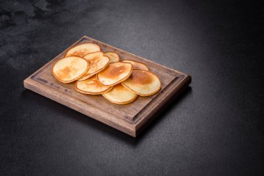 Tahta kesme tahtasının üzerinde nefis taze krepler ve koyu beton arka planda şeker.