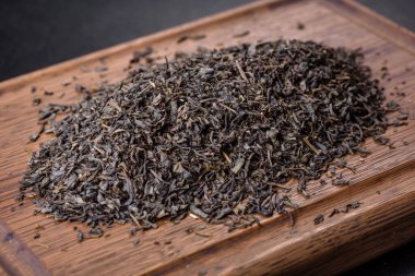 Koyu beton arka planda, ahşap kesme tahtasının üzerinde çay yeşili kuru.