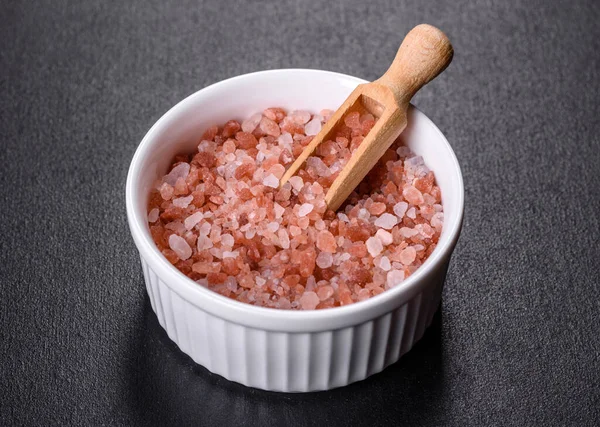 Siyah beton arka planda beyaz bir fincan tabağında büyük pembe Himalaya tuzu