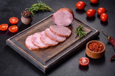 Lezzetli taze jambon. Koyu beton arka planda tahta kesme tahtasının üzerinde dilimler var.