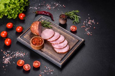 Lezzetli taze jambon. Koyu beton arka planda tahta kesme tahtasının üzerinde dilimler var.