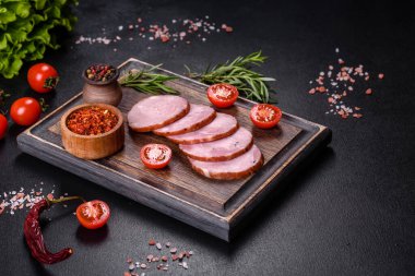 Lezzetli taze jambon. Koyu beton arka planda tahta kesme tahtasının üzerinde dilimler var.