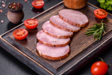 Lezzetli taze jambon. Koyu beton arka planda tahta kesme tahtasının üzerinde dilimler var.